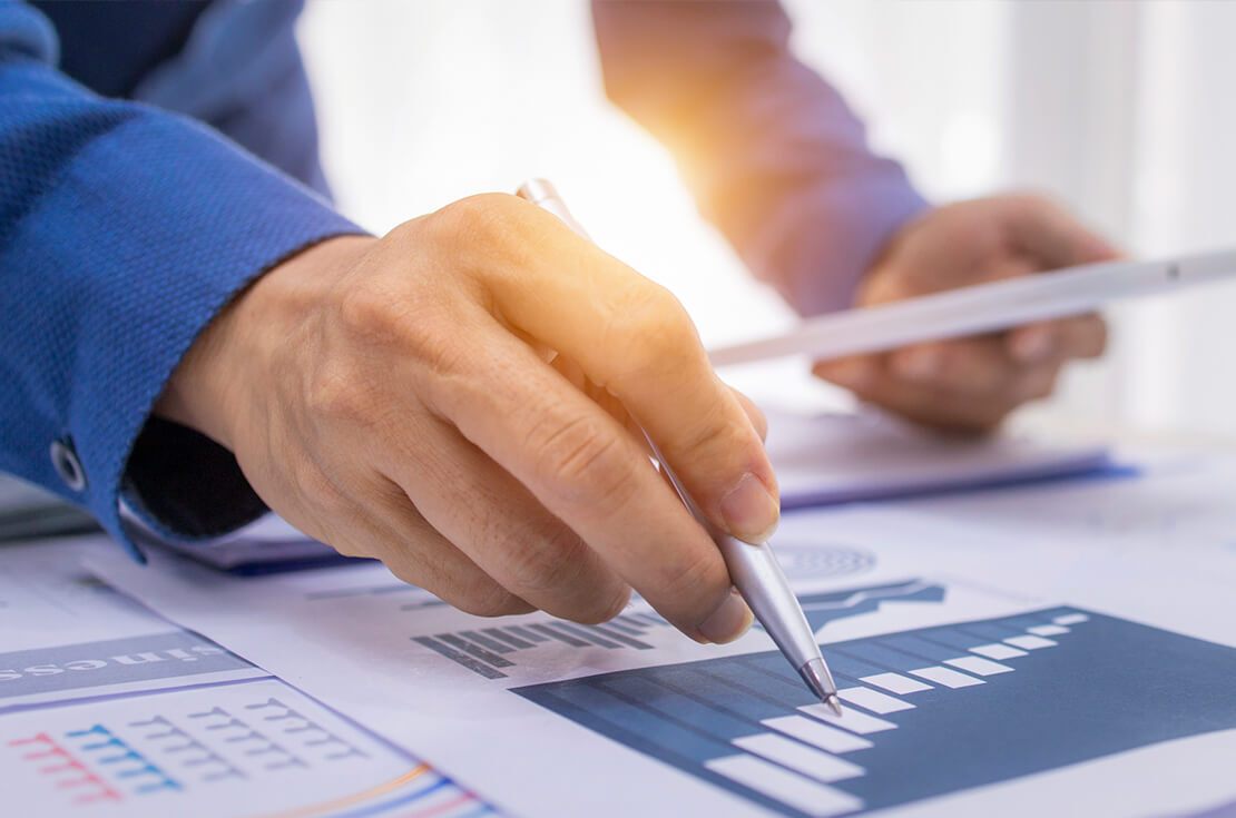 advisor analyzing investment charts with calculator and laptop